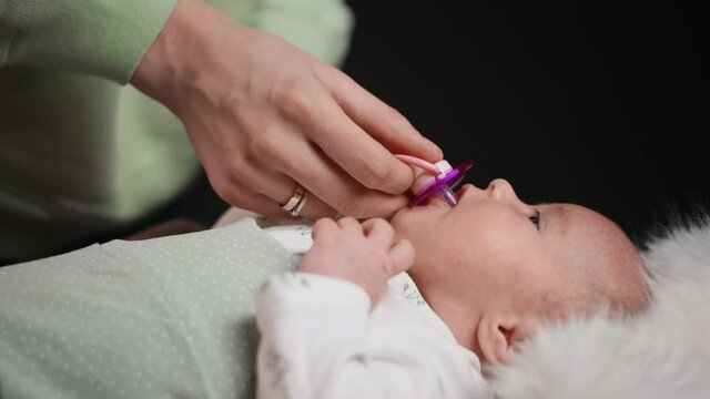Mom gives a pacifier to her newborn baby. Close-up.