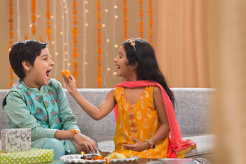 little sister giving laddo to her brother on Raksha Bandhan	