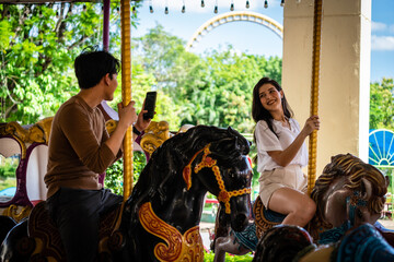 The asian couple lover happily sitting in the carousel of the amusement park and shooting photography with mobile phone © jiradet_ponari