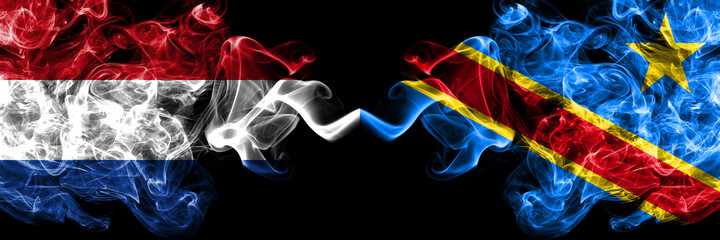 Netherlands vs Democratic Republic of the Congo smoky mystic flags placed side by side. Thick colored silky abstract smoke flags.