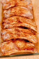 fried with spices pork ribs in a glass baking sheet on a wooden background. cooked meat at home. Barbecue.