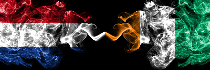 Netherlands vs Ivory Coast smoky mystic flags placed side by side. Thick colored silky abstract smoke flags.