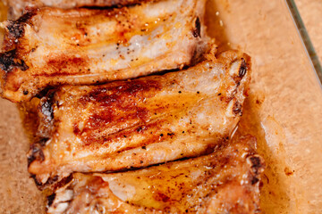 fried with spices pork ribs in a glass baking sheet on a wooden background. cooked meat at home. Barbecue.