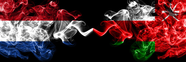 Netherlands vs Oman smoky mystic flags placed side by side. Thick colored silky abstract smoke flags.
