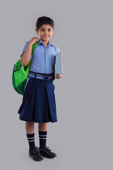 portrait of a school girl holding bag and books smiling 	
