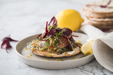 Gravlax Graved Lachs auf Knäckebrot mit Rote Beete Blätter Salat, Dill, Fischkäse, Skandinavische Senf Soße, Zitrone auf hell Marmor Hintergrund mit Leinen Tuch als Vorspeise oder Snack
