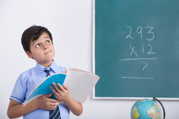 school boy solving maths question on blackboard	