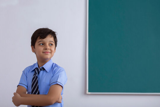 School Boy Standing In Front Of Blackboard	