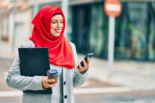 Young arab businesswoman using smartphone and drinking coffee at the city.