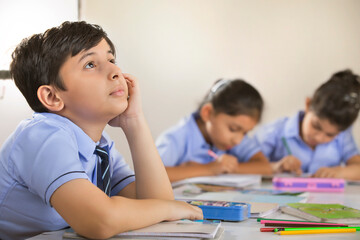 school boy thinking about something in the classroom	