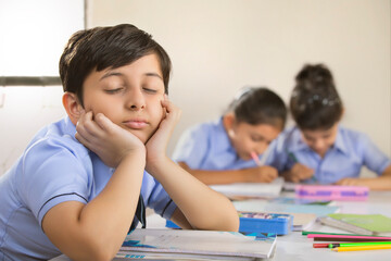 school boy sitting with eyes closed in class 	