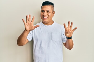 Fototapeta premium Young latin man wearing casual white t shirt showing and pointing up with fingers number nine while smiling confident and happy.