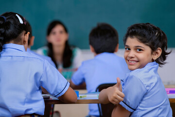 school girl smiling while teacher is sitting in class	