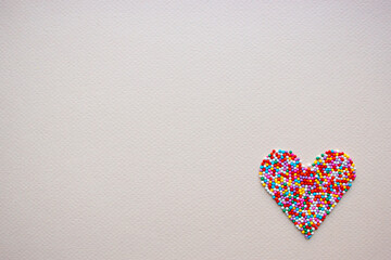 Heart made from pastry sprinkles on a light background.