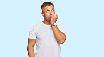 Handsome muscle man wearing casual white tshirt looking stressed and nervous with hands on mouth biting nails. anxiety problem.