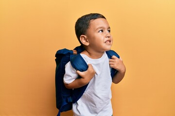 Adorable latin toddler smiling happy wearing student backpack over isolated yellow background.