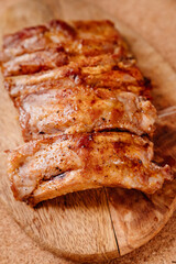 fried with spices pork ribs in a glass baking sheet on a wooden cutting board. cooked meat at home. Barbecue.