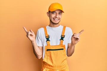 Hispanic young man wearing handyman uniform smiling confident pointing with fingers to different directions. copy space for advertisement