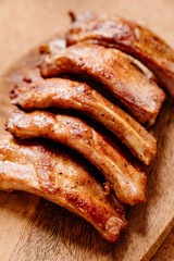 fried with spices pork ribs in a glass baking sheet on a wooden cutting board. cooked meat at home. Barbecue.