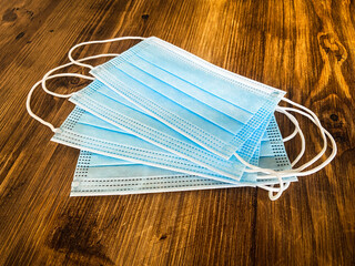 Disposable covid protective masks lie on top of a woooden table