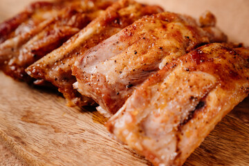 fried with spices pork ribs in a glass baking sheet on a wooden cutting board. cooked meat at home. Barbecue.
