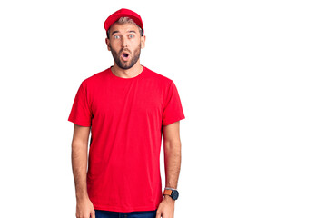 Young handsome blond man wearing t-shirt and cap afraid and shocked with surprise expression, fear and excited face.