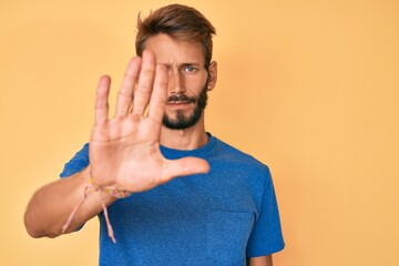 Handsome caucasian man with beard wearing casual clothes doing stop sing with palm of the hand....