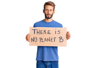 Handsome blond man with beard holding there is no planet b banner thinking attitude and sober expression looking self confident