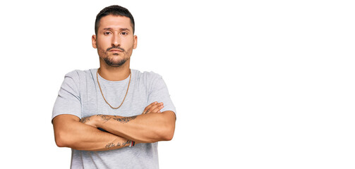 Handsome man with tattoos wearing 90s style skeptic and nervous, disapproving expression on face with crossed arms. negative person.