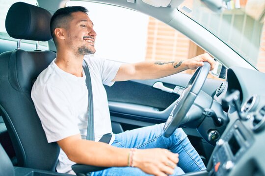 Young Hispanic Man Smiling Happy Driving Car.