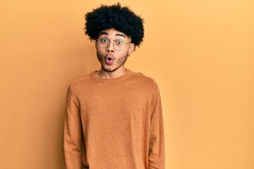 Obraz na płótnie Canvas Young african american man with afro hair wearing casual winter sweater afraid and shocked with surprise expression, fear and excited face.