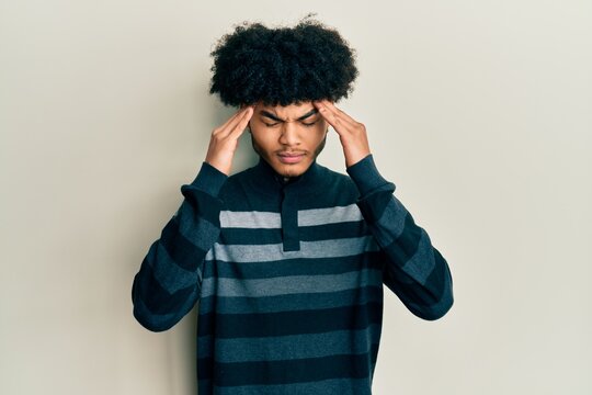 Young african american man with afro hair wearing casual clothes with hand on head for pain in head because stress. suffering migraine.