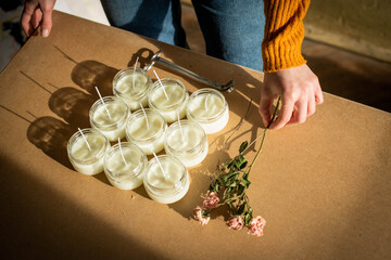 Handmade candle from paraffin and soy wax in glass with flowers and tools on craft background. Let flay. Candle making