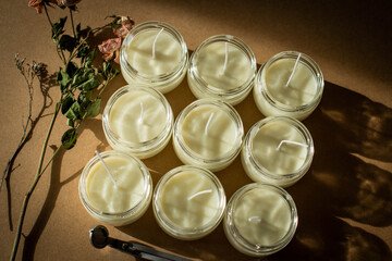 Handmade candle from paraffin and soy wax in glass with flowers and tools on craft background. Let flay. Candle making