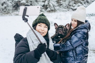 Two young girls take a selfie with their dog against the backdrop of a snowy winter landscape in the open air.Winter lifestyle.Holiday during the Christmas holidays. local travel.healthy break