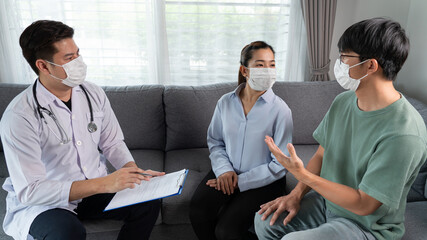 Asian doctor and couple looking and discussing over clipboard to marriage advice during a therapy...