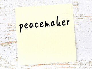 Yellow sheet of paper with word peacemaker. Reminder concept