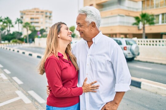 Middle age hispanic couple smiling happy and hugging walking at street.