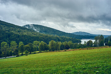 View from the clearing to the forested mountains and the lake during cloudy weather