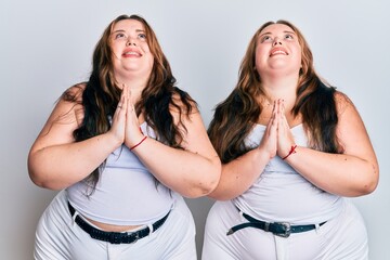 Plus size caucasian sisters woman wearing casual white clothes begging and praying with hands together with hope expression on face very emotional and worried. begging.