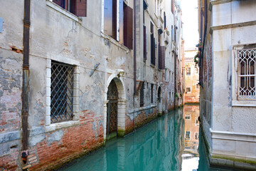 Fototapeta na wymiar Small narrow canal between buildings in Venice in Italy