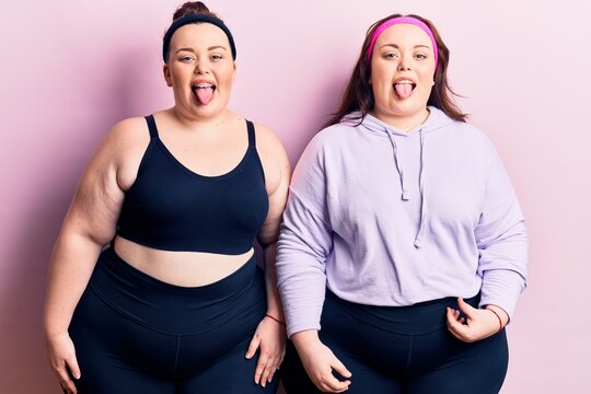 Young plus size twins wearing sportswear sticking tongue out happy with funny expression. emotion concept.