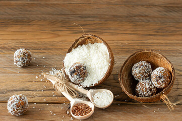 Healthy food concept. Homemade coconut energy balls in cocnut shell on wooden background.
