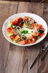 A tasty Greek salad with fresh vegetables: tomato, cucumber, red bel pepper, lettuce, onion, olives...