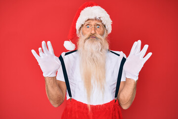 Fototapeta na wymiar Old senior man wearing santa claus costume with suspenders puffing cheeks with funny face. mouth inflated with air, catching air.