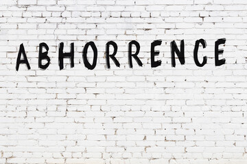 Inscription abhorrence painted on white brick wall