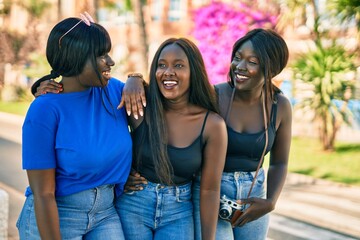 Three african american friends smiling happy hugging at the city.