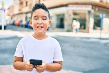 Adorable boy smiling happy using smartphone at street of city.