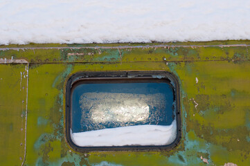 The frozen snow-covered window of the iron house
