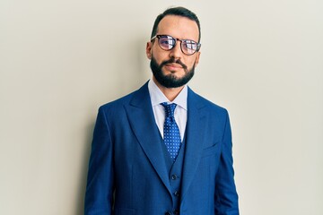 Young man with beard wearing business suit and tie relaxed with serious expression on face. simple and natural looking at the camera.